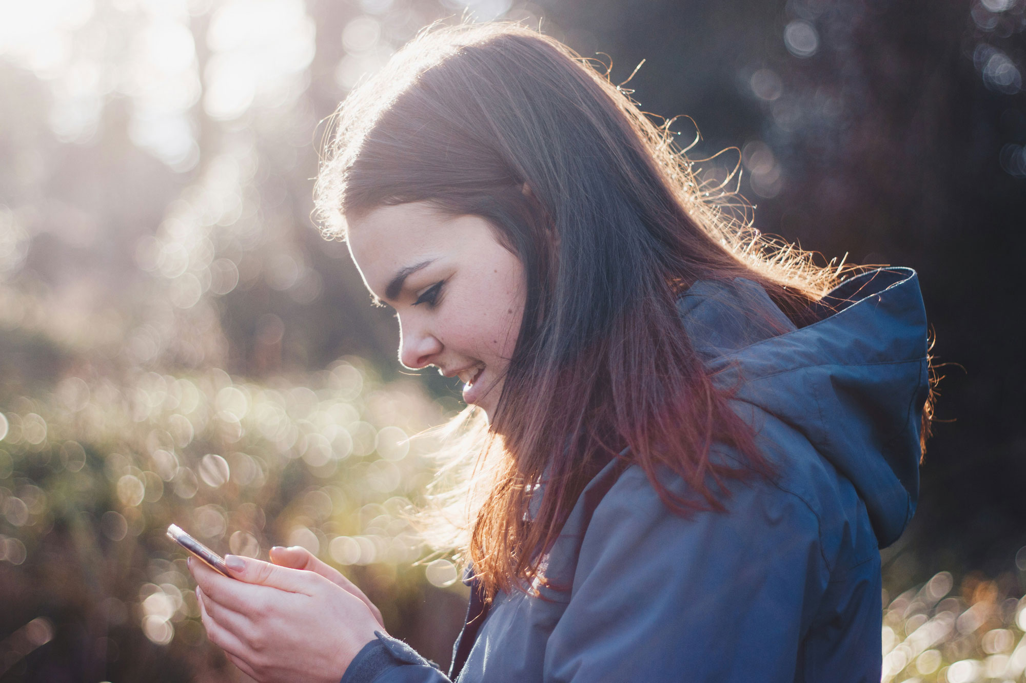Frau hält Telefon lächelnd in der Hand